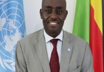 Official photo of Chris Mburu standing in between the UN and DRC flags.