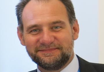 صورة رسمية لزلاتان ميليشيتش تظهره يبتسم أمام الكاميرا.