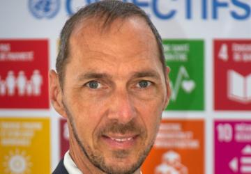 Un hombre delante de un cartel con los logotipos de los ODS.