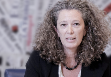 امرأة ترتدي سترة سوداء وتجلس وسط خلفية ضبابية.