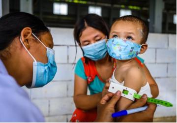 ممرضة تقوم بتلقيح طفل صغير بينما تمسكه أمه.