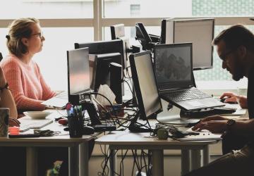 A group of people work on their computers in an office.