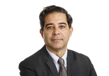 Un hombre con corbata y traje, funcionario de las Naciones Unidas, sonríe para la cámara.