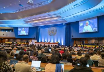 A picture of a conference room with an image of a woman projected on the screen.