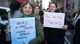 Deux manifestantes brandissent des pancartes en souriant à la caméra.
