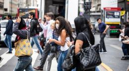 Crowds crossing the road in Argentina. One woman wears a protective face mask.