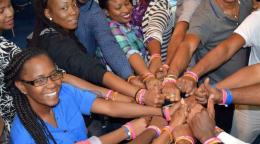 A group of women and men put their arms together to show solidarity towards their commitment to end gender-based violence in Trinidad and Tobago.