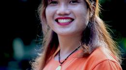 Primer plano de Kim Thuy, quien tiene una gran sonrisa en su rostro, mirando a la cámara. Kim Thuy es una activista transgénero de Vietnam que sueña con organizar un desfile del orgullo gay en la comunidad donde creció.