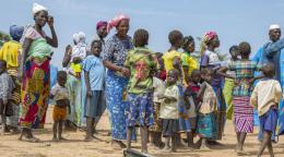 A group of women, men and children gather outside in a camp in the northeast of the country.