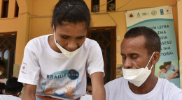 A woman in a white face mask leans over a man in a white face mask.