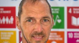 Un hombre delante de un cartel con los logotipos de los ODS.