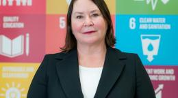 Una mujer está delante de un cartel con los logos de los ODS.