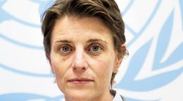 Una mujer delante de una bandera de las Naciones Unidas.