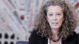 Una mujer con chaqueta negra está sentada en el fondo borroso.