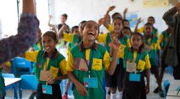 Grupo de niños y niñas de pie en un aula.