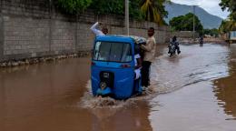 Two boys standing inside a motor vehicle that is stuck in the middle of a flood