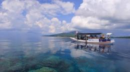 A small boat on a body of water, with bright clouds reflecting on the water