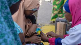 A mother holds her child as a doctor gives her an injection.