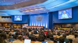 A picture of a conference room with an image of a woman projected on the screen.