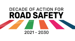 A logo with the text "Decade of Action for Road Safety" along with the colours of the SDGs marked as lines on a zebra crossing.
