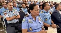 A group of police officers in blue uniforms and badges/ emblems gathered in a meeting room
