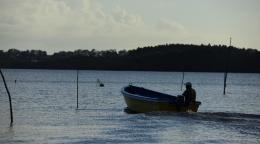 A man on a boat is traveling across water.