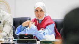 حياة، متطوّعة ترتدي سترة حمراء، تتحدث خلال اجتماع على طاولة للمؤتمرات.