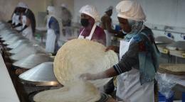 A group of women are cooking in a hot steaming room 
