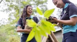 Two girls standing next to green plant