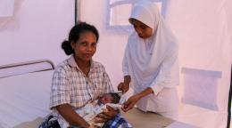 ممرضة تعتني بطفلٍ حديث الولادة وأمّه