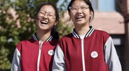 Две девочки в школьной форме весело смеются