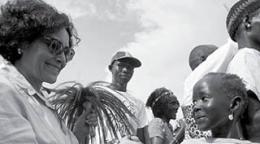 Portada del documento con una fotografía en blanco y negro que muestra a una multitud y a una niña y una mujer estrechando sus manos en primer plano. 
