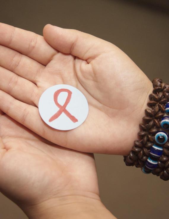 A picture of two palms in each other holding a little circle with a HIV symbol in it