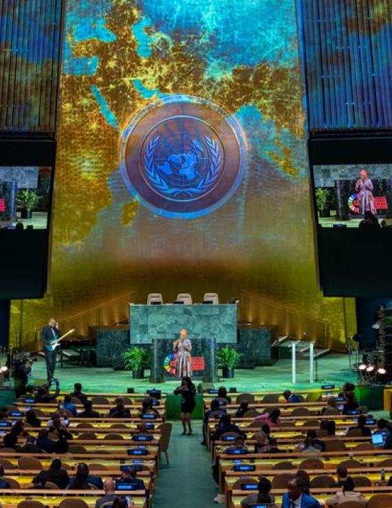 Two people on stage at the UN General Assembly hall. 