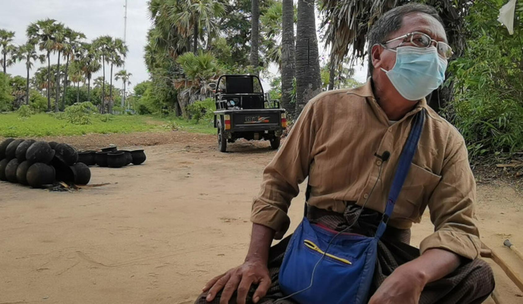 戴着面罩的吴卓在农田前坐下。