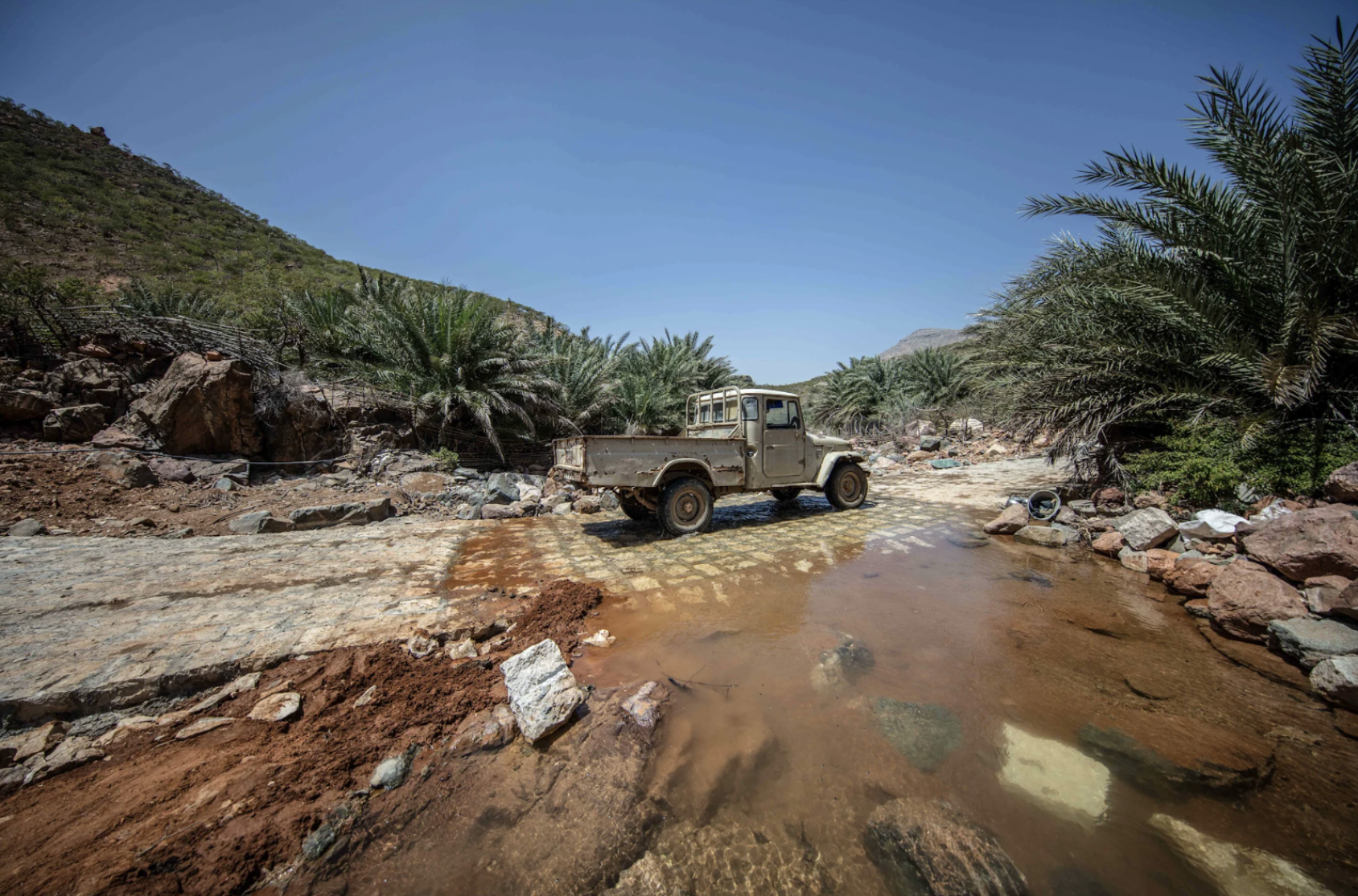 Une fourgonnette circule sur une route partiellement détruite.