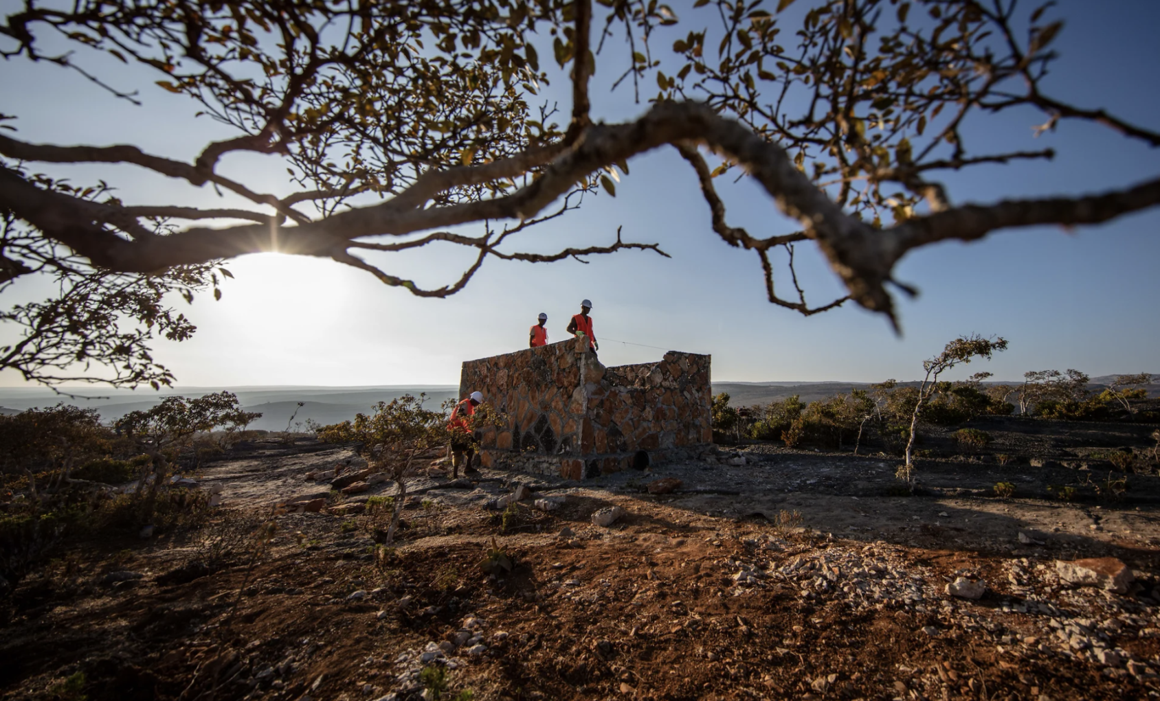 Trois ouvriers travaillent à la construction d'un réservoir d'eau de forme carrée.