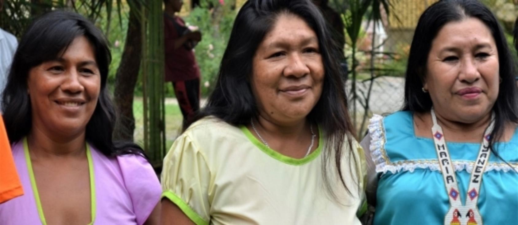 Tres mujeres con ropas coloridas sonríen a la cámara.