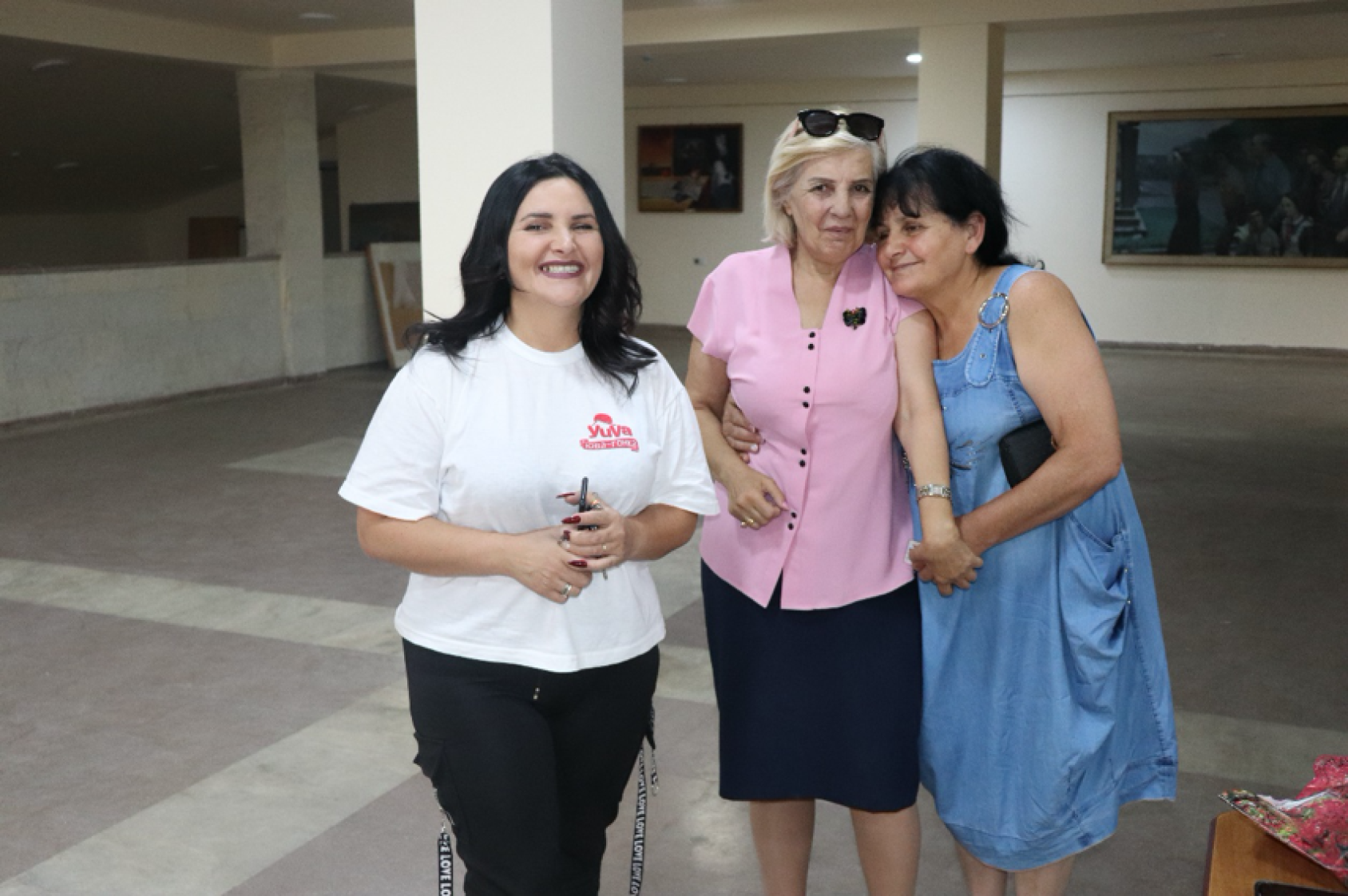 Tres mujeres, una cerca de la otra, sonríen a la cámara.