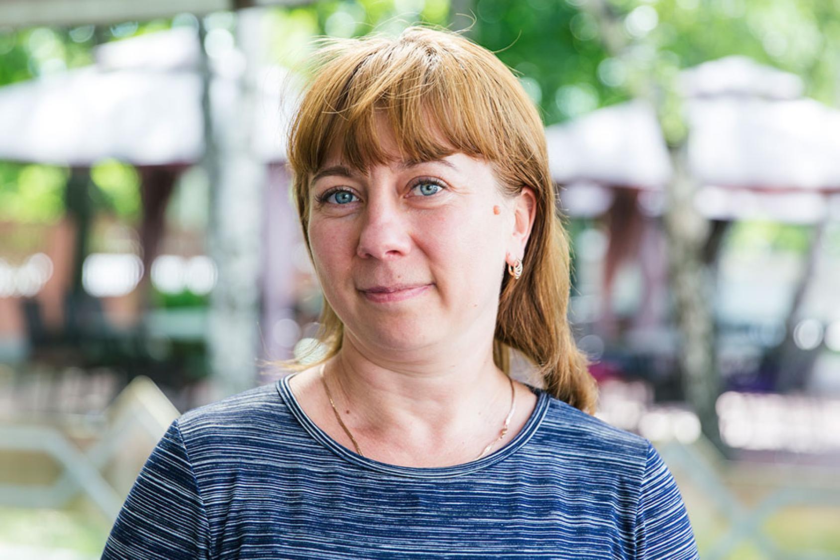 A woman wearing a blue shirt looks straight at the camera. 