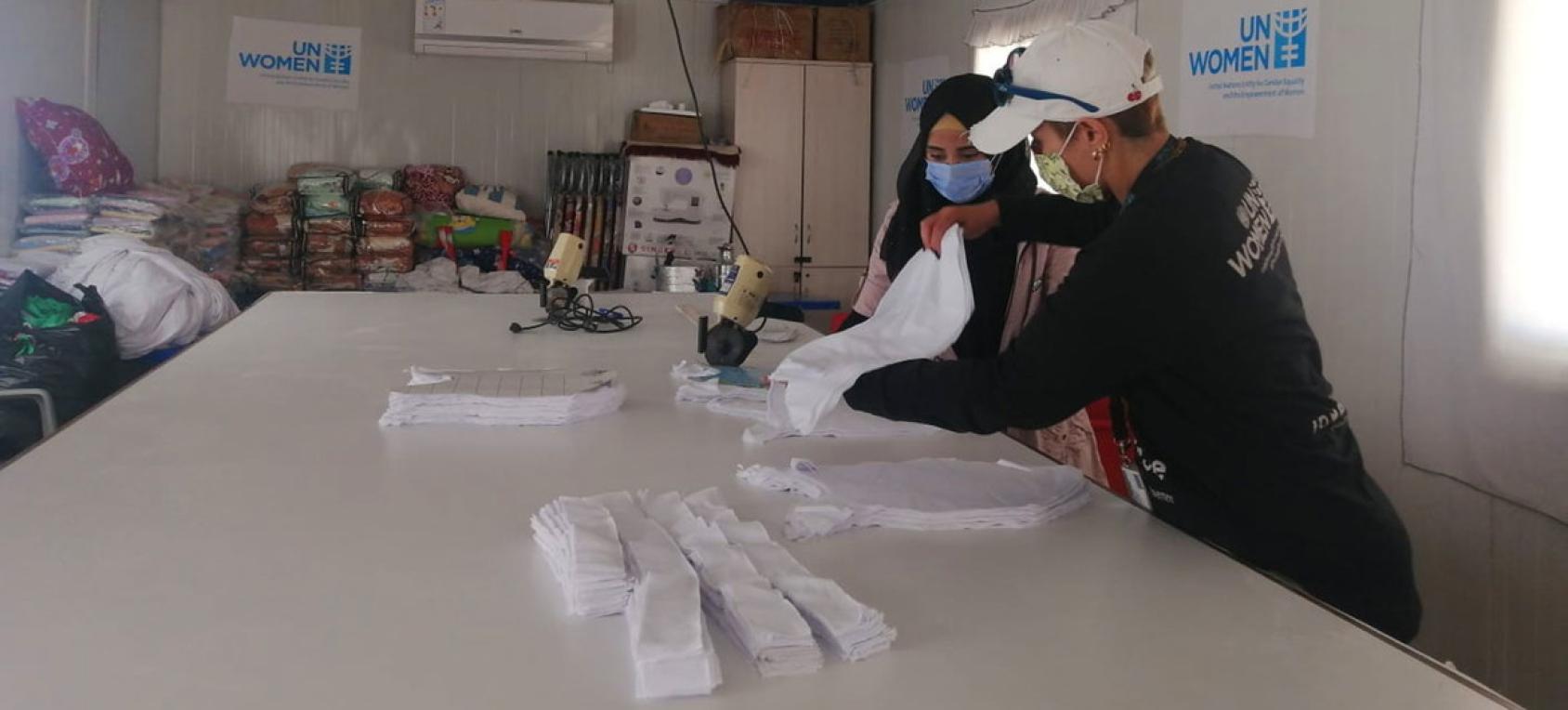 两个人在一张白色桌子上一起工作，看着一些用品。