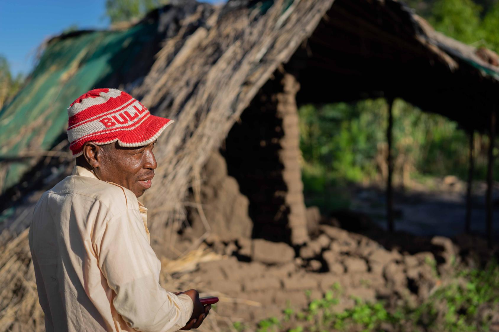 A man stands near the ruins of a house impacted by a hurricane.