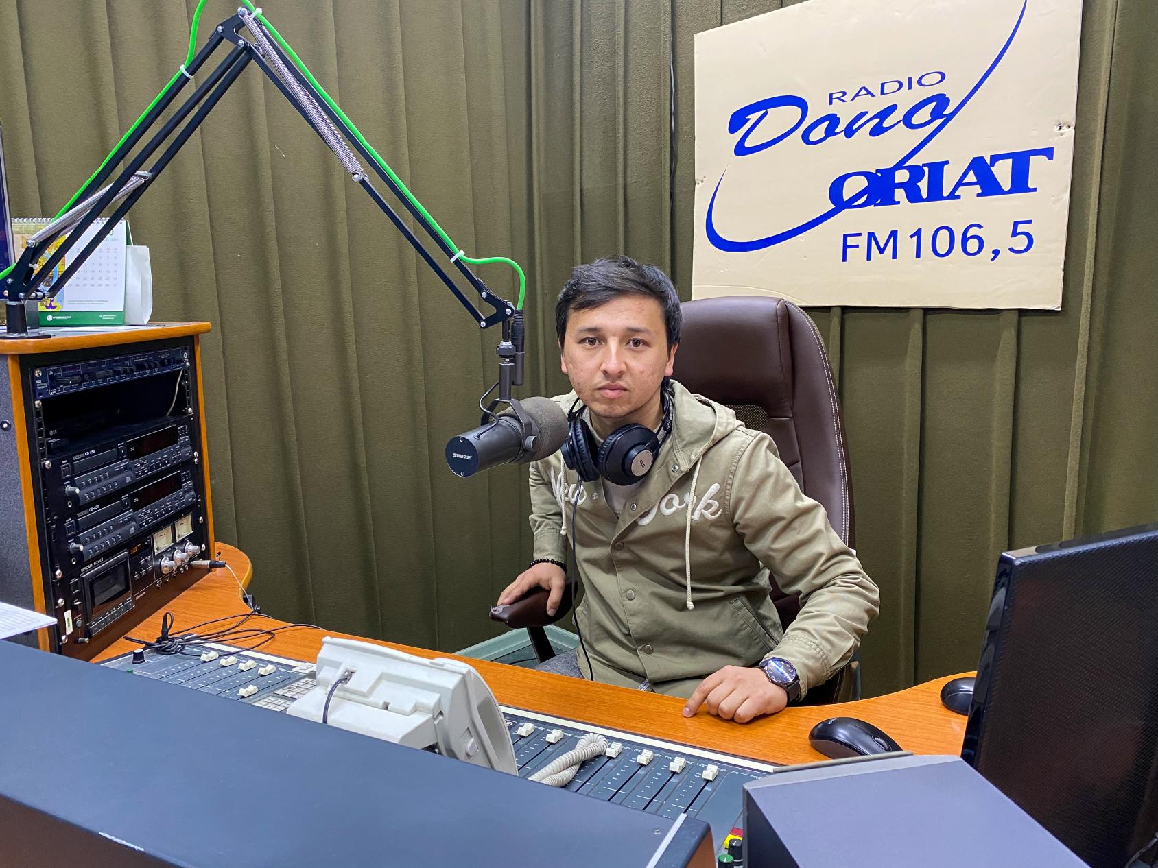 молодой мужчина за пультом в радиостудии.