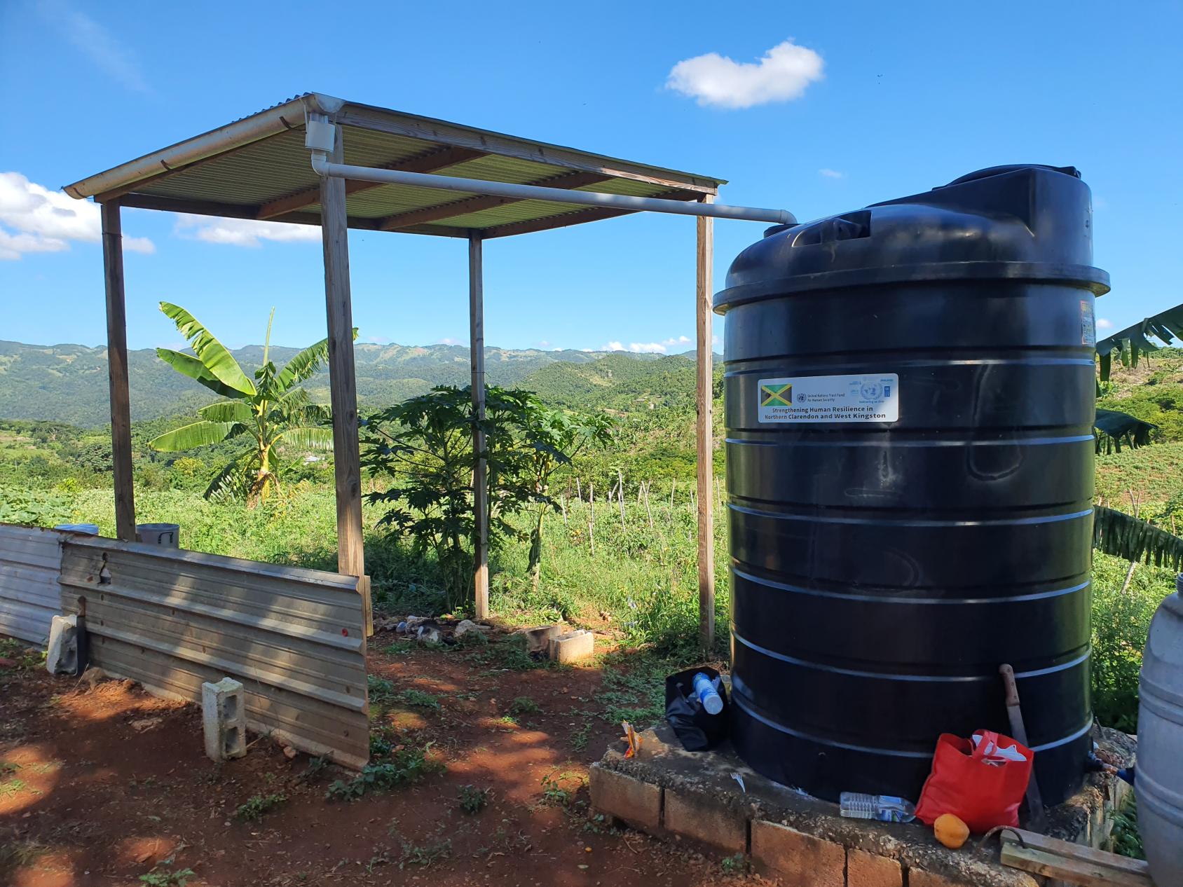Le toit d’un abri recueille l'eau de pluie, qui s'écoule ensuite dans un tuyau pour être acheminée jusque dans un grand réservoir de stockage noir. 