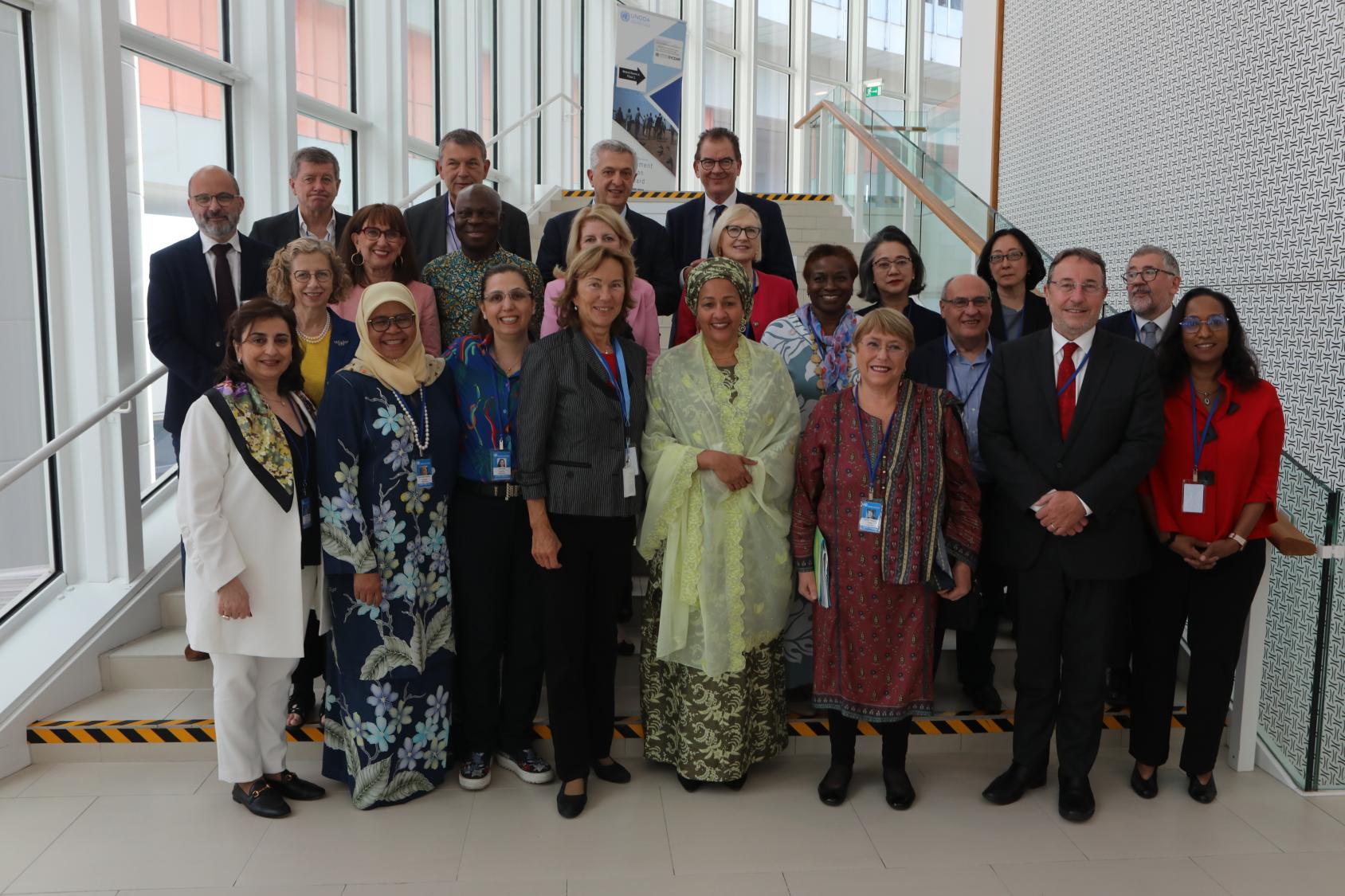 Un grupo de funcionarios de la ONU posan juntos para una foto, junto a una alta hilera de ventanas de cristal.