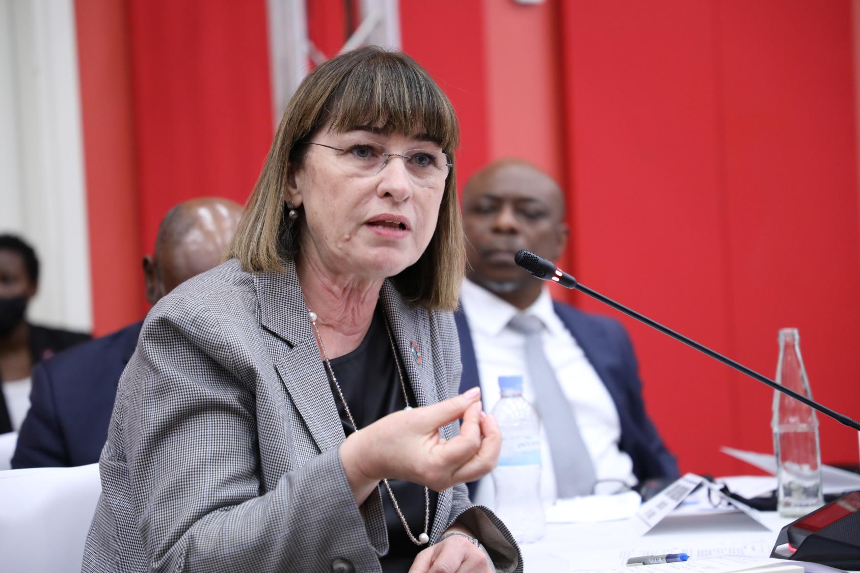 Una mujer con traje de chaqueta habla por un micrófono.