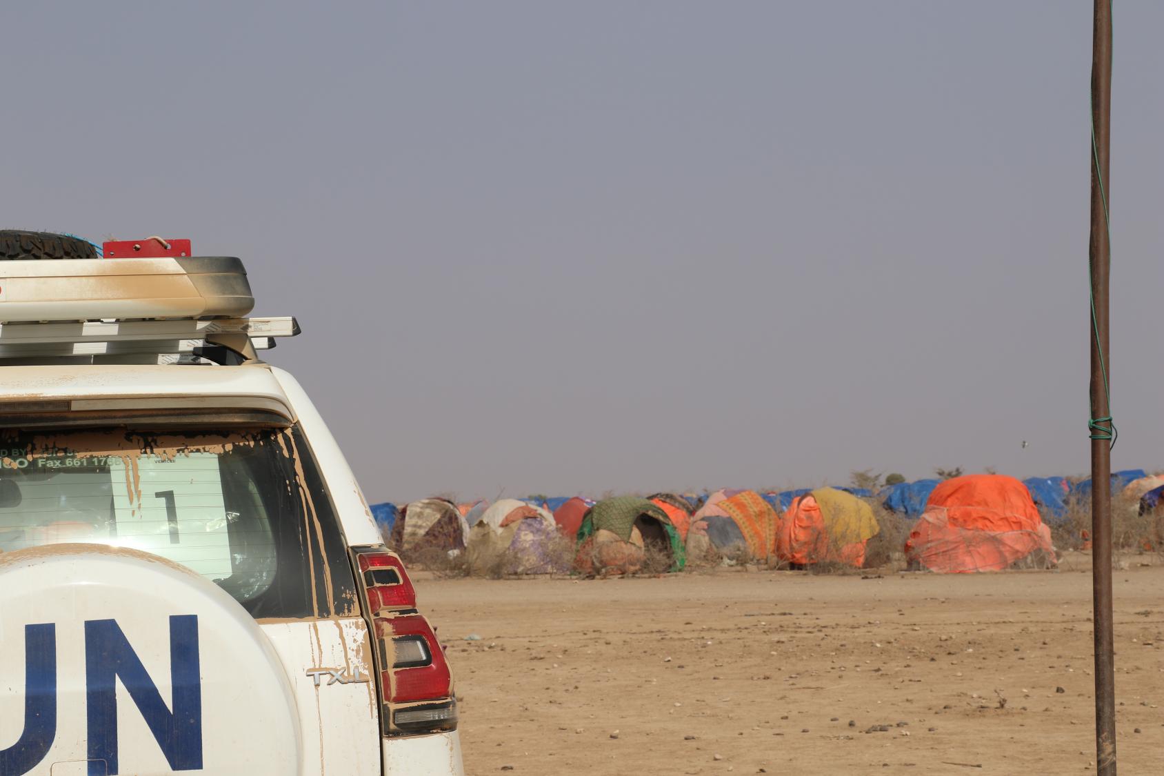 A jeep with UN logo drives through a desert. 