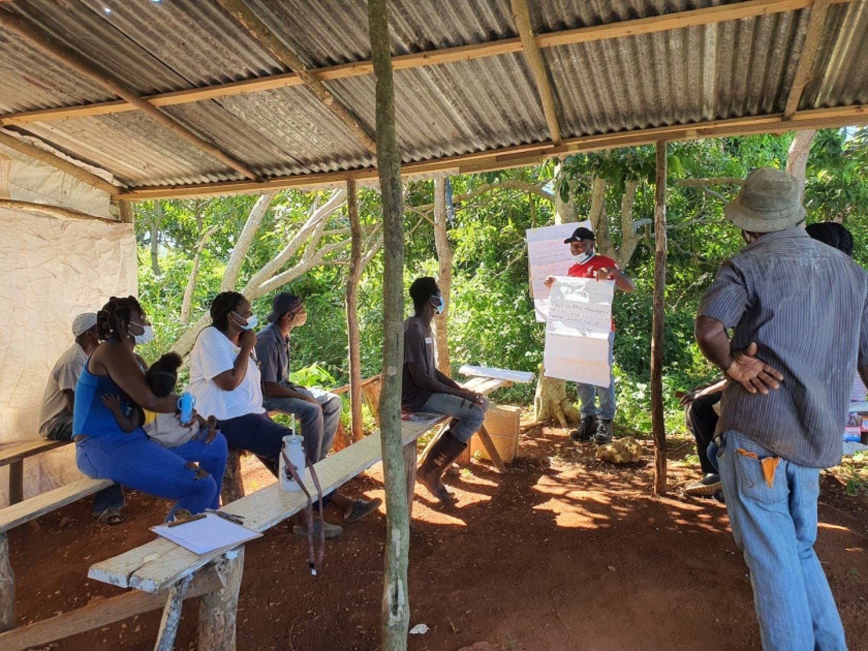 Des hommes et des femmes participent à une réunion matinale dans un petit hangar.