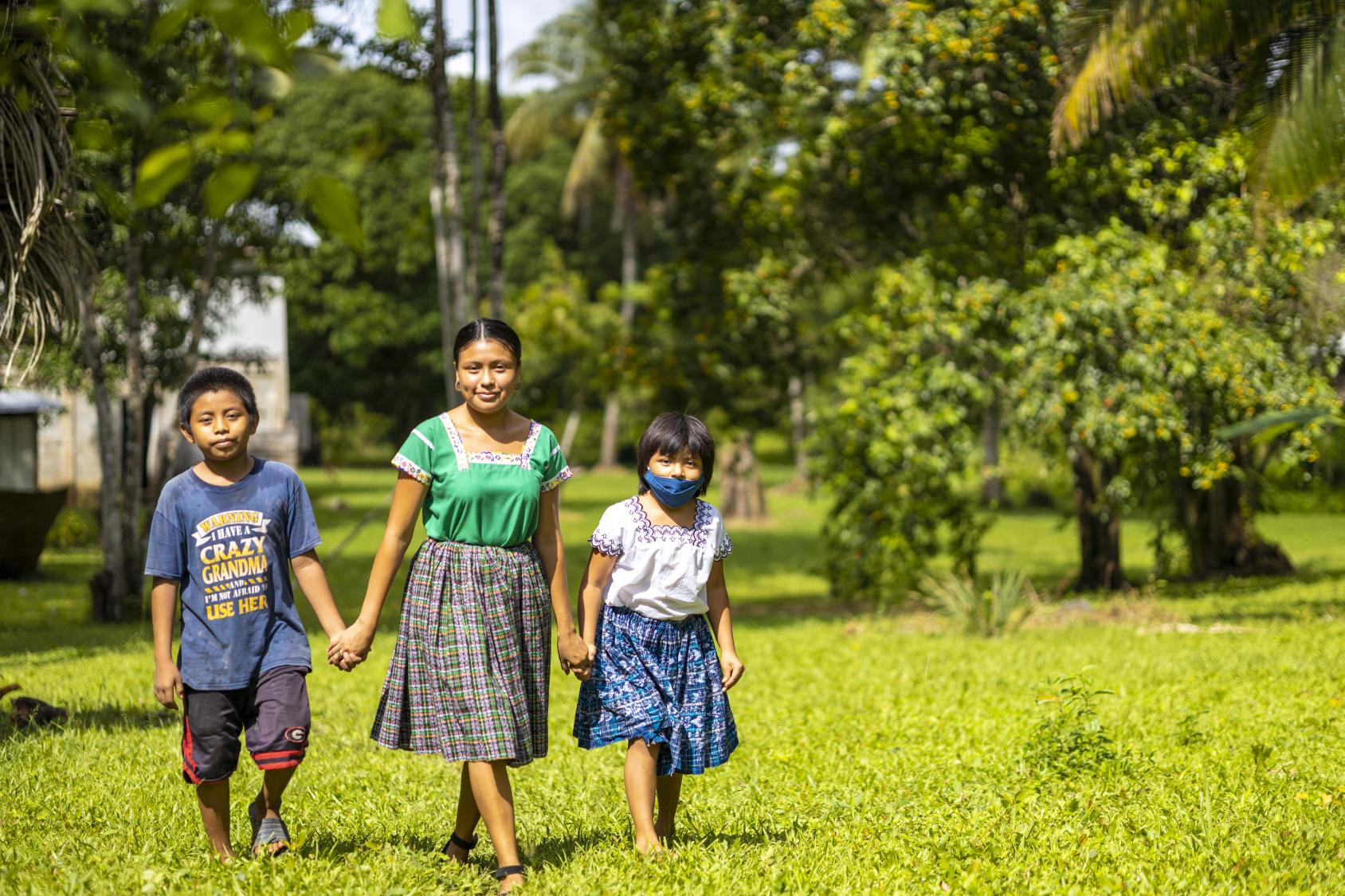 Una joven, uno niña y una niña caminando en una zona de césped