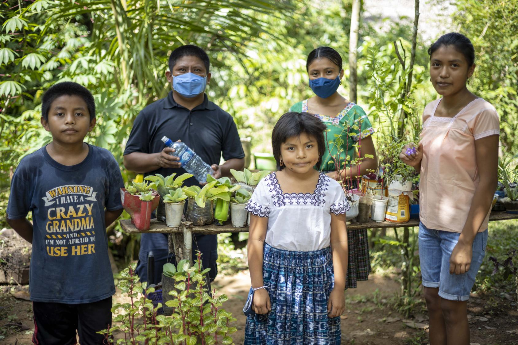 Un grupo de personas con mascarillas en un área verde.